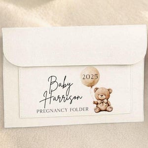 May include: White pregnancy folder featuring a teddy bear and balloon design. The text "Baby Harrison" and "Pregnancy Folder" is printed on the folder. The balloon has the year "2025" printed on it.