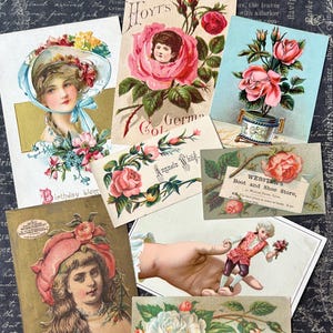 May include: A collection of vintage postcards featuring floral designs and portraits of women. The cards showcase illustrations of roses, portraits, and decorative text, with a color palette of pink, blue, and gold.