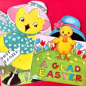 May include: Two vintage Easter greeting cards. One features a yellow chick wearing a bonnet and holding a sign that says "Happy Easter." The other shows a yellow duckling with a blue hat and the words "A Glad Easter."