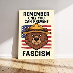 May include: Poster featuring a brown bear wearing a ranger hat with the text "REMEMBER ONLY YOU CAN PREVENT FASCISM" over an American flag design. The hat reads "NO KINGS". The bear has an angry expression.