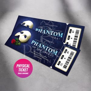 May include: Two blue Phantom of the Opera tickets featuring white masks and a red rose. The tickets display the text "PHANTOM OF THE OPERA" and "HIS MAJESTY'S THEATRE LONDON". A pink circle reads "PHYSICAL TICKET (MOCK SOUVENIR)".