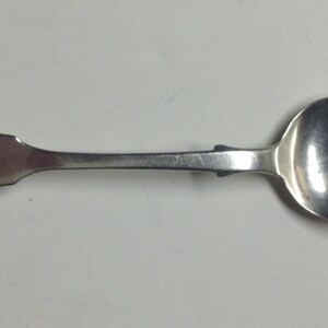 Puede incluir: Una cuchara de plata con un cuenco redondeado y un mango largo y delgado. El mango est&aacute; grabado con la palabra "JOHN".