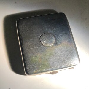 Pu&ograve; includere: Un porta sigarette d'argento con un design circolare sulla parte superiore.
