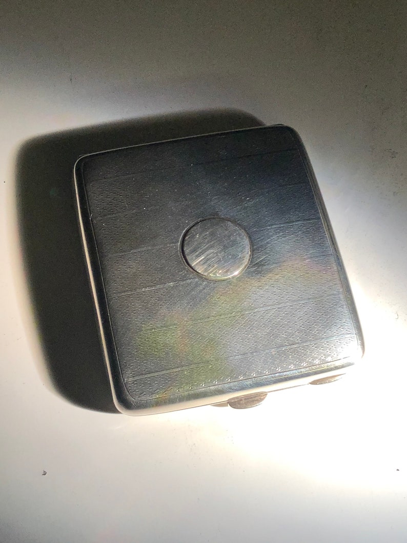 Pu&ograve; includere: Un porta sigarette d'argento con un design circolare sulla parte superiore.