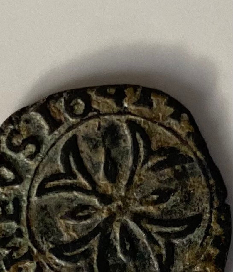 May include: Close-up of a circular, bronze-coloured coin with a five-pointed star design in the centre. The coin has a raised rim with lettering around the edge.