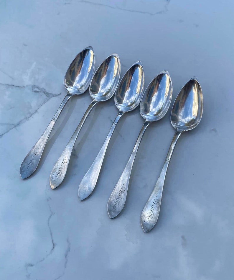 May include: Five silver spoons with ornate handles. Each spoon has the inscription "Grandmother" on the handle.