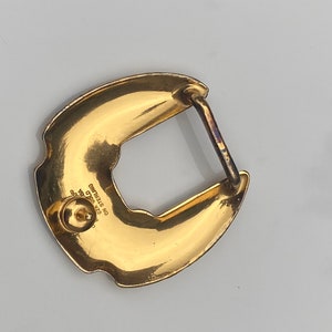 May include: Gold-toned metal belt buckle with a horseshoe design. The buckle has a textured surface and the words "STERLING NO. 925 GOLD" are engraved on the back.