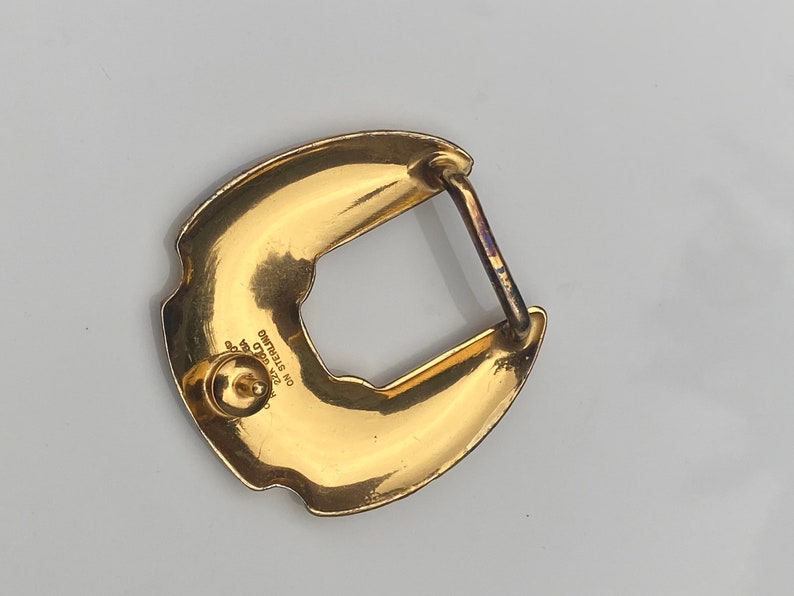 May include: Gold-toned metal belt buckle with a horseshoe design. The buckle has a textured surface and the words "STERLING NO. 925 GOLD" are engraved on the back.