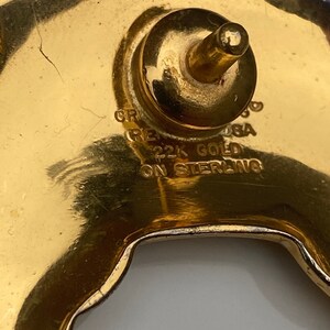 May include: Close-up of a gold-toned metal buckle with the text "22K GOLD ON STERLING" engraved on the back.