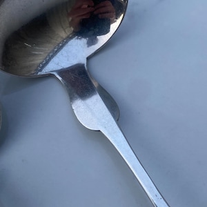 May include: A silver serving spoon with a rounded bowl and a long, slender handle.