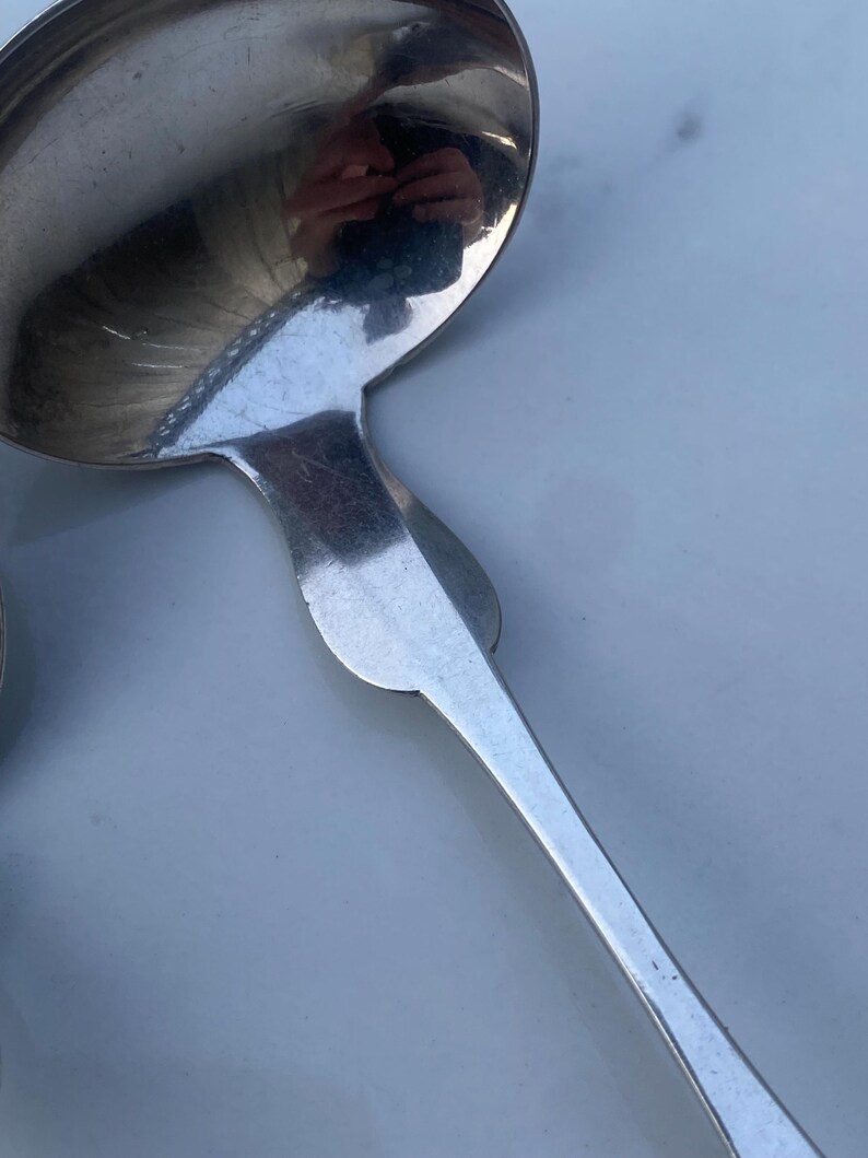 May include: A silver serving spoon with a rounded bowl and a long, slender handle.
