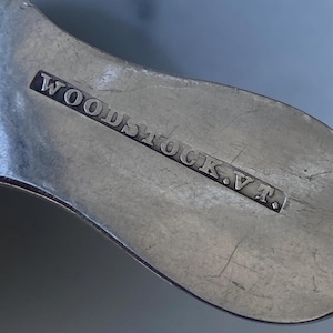 May include: Close-up of a silver spoon with the inscription "WOODSTOCK, V.T."