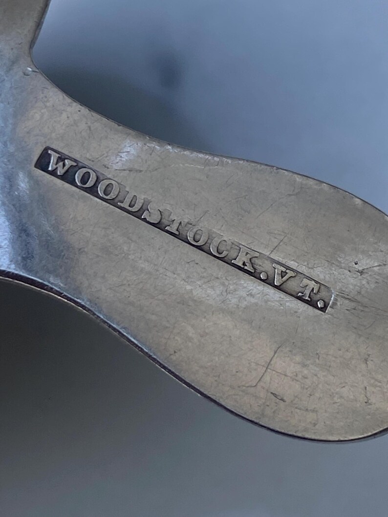 May include: Close-up of a silver spoon with the inscription "WOODSTOCK, V.T."
