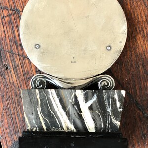 May include: A silver circular mirror with a black and white marble base and a black wooden base. The mirror has a silver inscription that reads "925 SILVER".