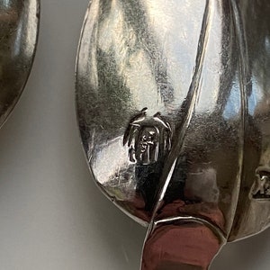May include: Close-up of a silver spoon with a leaf design. The spoon has a mark on the back that reads "Sterling 925".