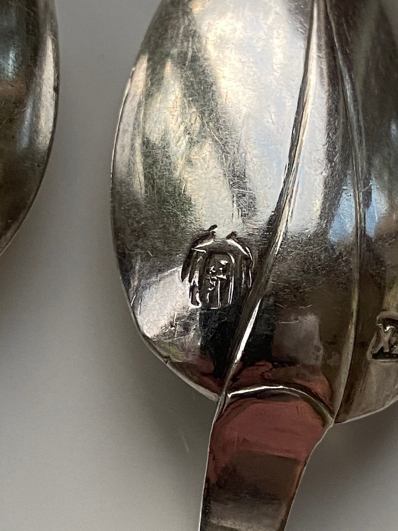 May include: Close-up of a silver spoon with a leaf design. The spoon has a mark on the back that reads "Sterling 925".