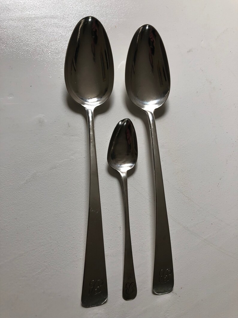 Puede incluir: Tres cucharas de plata de diferentes tama&ntilde;os, todas con un cuenco redondeado y un mango largo y delgado. Los mangos est&aacute;n grabados con el n&uacute;mero "88".