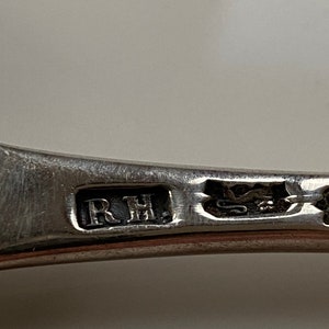 K&ouml;nnte beinhalten: Nahaufnahme eines silbernen L&ouml;ffels mit den eingravierten Initialen "R.H.".