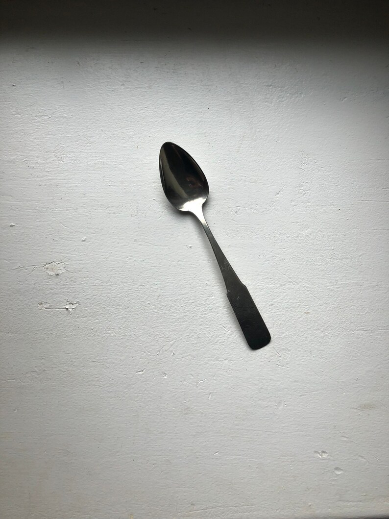 Puede incluir: Una cuchara de plata con un cuenco redondeado y un mango largo y delgado.