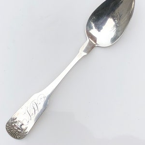May include: A silver teaspoon with an ornate handle and the inscription "W.D." on the back.