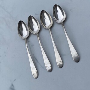 May include: Four silver spoons with the initials "E.H." engraved on the back of each spoon.