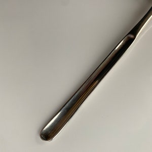 K&ouml;nnte beinhalten: Nahaufnahme eines silbernen medizinischen Instruments aus Metall mit abgerundeter Spitze.