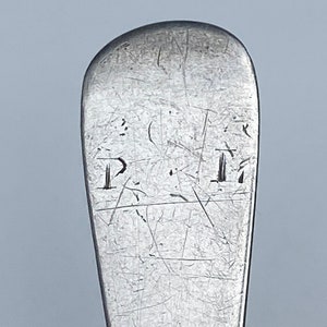 K&ouml;nnte beinhalten: Nahaufnahme der Oberseite eines silbernen L&ouml;ffels mit der Inschrift "I.M." auf der R&uuml;ckseite.