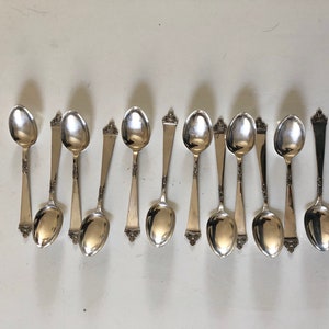 Puede incluir: Un juego de doce cucharaditas de plata con mangos adornados.