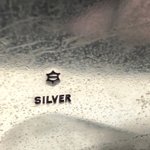 May include: Close-up of a silver object with a star-shaped mark and the word "SILVER" inscribed on it.
