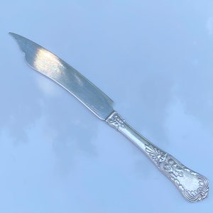 May include: A silver butter knife with an ornate handle and a slightly curved blade. The knife is marked "Gorham" on the blade.