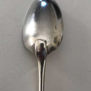 Może przedstawiać: Srebrna łyżka z zaokrągloną miseczką i długim, smukłym trzonkiem. Łyżka wykonana jest z błyszczącego, odblaskowego metalu, prawdopodobnie ze stali nierdzewnej lub srebra. Łyżka jest przeznaczona do jedzenia.