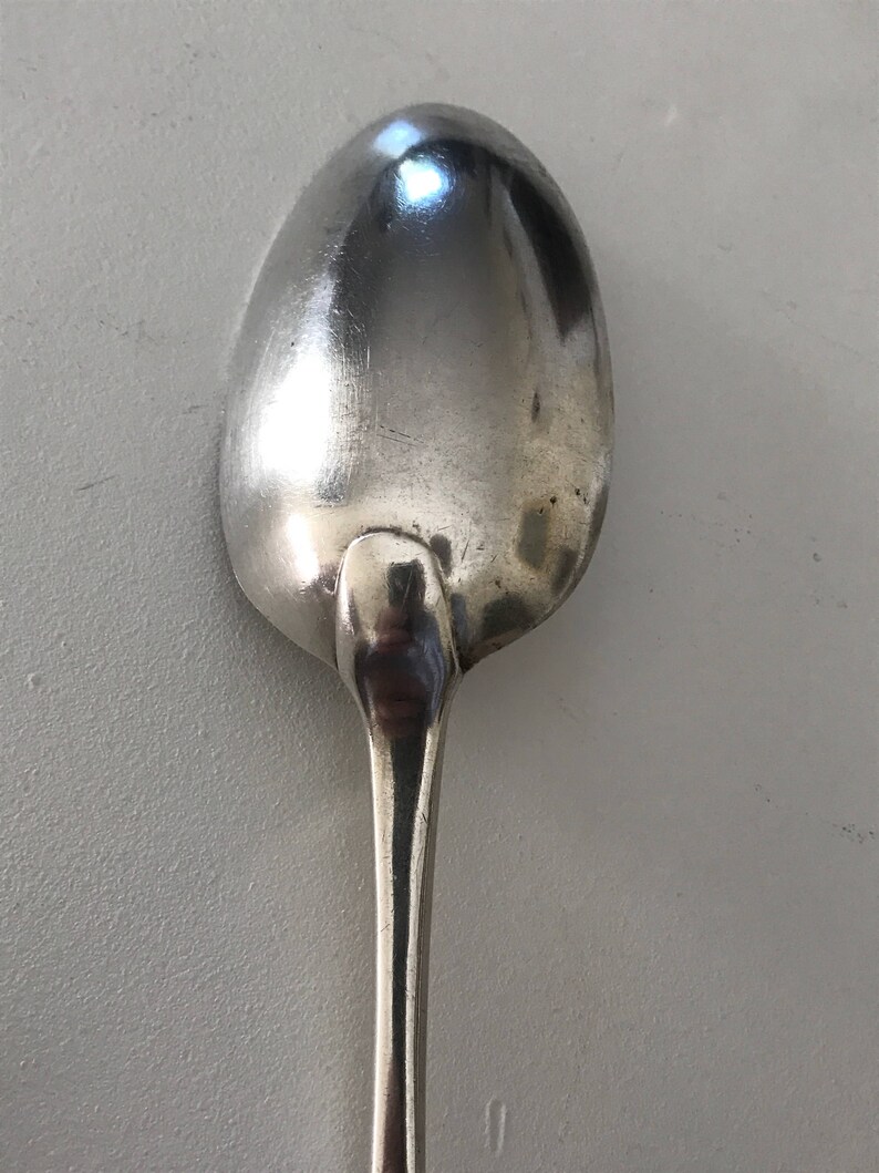 Może przedstawiać: Srebrna łyżka z zaokrągloną miseczką i długim, smukłym trzonkiem. Łyżka wykonana jest z błyszczącego, odblaskowego metalu, prawdopodobnie ze stali nierdzewnej lub srebra. Łyżka jest przeznaczona do jedzenia.