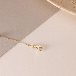 May include: A gold-toned metal chain necklace featuring a delicate link design and a secure lobster claw clasp. The chain is thin and polished, showcasing a consistent metallic finish throughout the entire length of the jewelry piece.