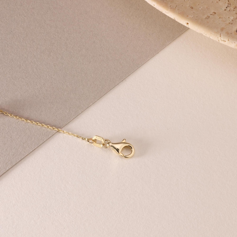May include: A gold-toned metal chain necklace featuring a delicate link design and a secure lobster claw clasp. The chain is thin and polished, showcasing a consistent metallic finish throughout the entire length of the jewelry piece.
