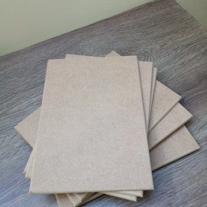 May include: A stack of five brown, rectangular pieces of wood. The wood is smooth and has a natural grain.