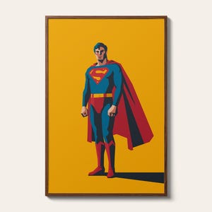 May include: A framed art print featuring a stylized illustration of Superman standing against a solid mustard yellow background. The character wears a blue suit with a red cape, a yellow belt, and the iconic red and yellow S-shield emblem on the chest.