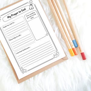 Close-up photo of the My Prayer to God printable worksheet on a clipboard with colored pencils beside it.