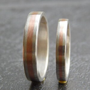 May include: Two silver wedding bands with a thin copper stripe down the center.