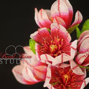 May include: A bouquet of pink and white beaded flowers with gold accents. The flowers are made with small beads and have a delicate, intricate design.