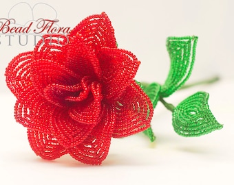 May include: A red beaded rose with green beaded leaves and stem. The rose is made of small, round beads and is very detailed.