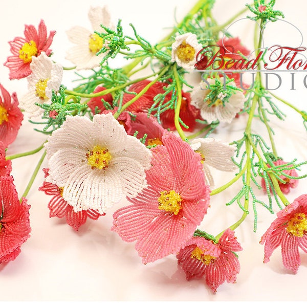 Pode incluir: Um ramo de flores de cosmos de contas em rosa e branco com caules verdes. As flores são feitas de contas pequenas e têm um aspecto delicado e realista. O ramo está disposto num vaso e está pronto para ser exibido.