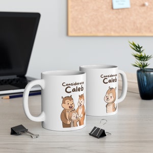 Könnte beinhalten: Zwei weiße Keramikbecher mit braunen Henkeln. Beide Becher zeigen ein Cartoon-Bild von drei Streifenhörnchen mit dem Text "Considerate Caleb" auf jedem Becher.