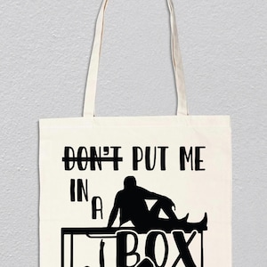 Puede incluir: Una bolsa de tela blanca con texto negro y una silueta de una persona sentada en una caja. El texto dice "No me pongas en una caja".