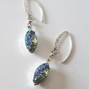 May include: A pair of silver dangle earrings with iridescent blue and green gemstone drops.