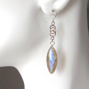 Puede incluir: Pendientes de plata con un diseño de alambre retorcido de plata y una piedra de labradorita azul iridiscente en forma de lágrima.