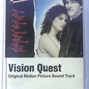 May include: A Vision Quest original motion picture soundtrack cassette tape. The cover features a couple and the title in a stylized font. The tracklist includes songs by Journey, Madonna, and Don Henley.