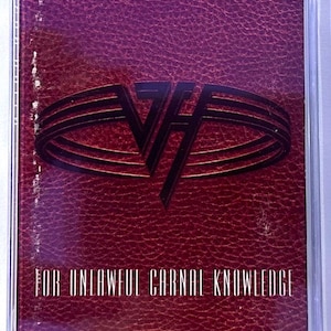 May include: A cassette tape with a burgundy leather-textured cover. The cover features a black logo and the text "FOR UNLAWFUL CARNAL KNOWLEDGE" in white. The cassette is encased in a clear plastic case.