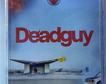 May include: A cassette tape with a surreal landscape scene. The cover features the word "Deadguy" in red, with a logo that says "Near Death Travel Services." A building with a flat roof and a car on fire are also visible.
