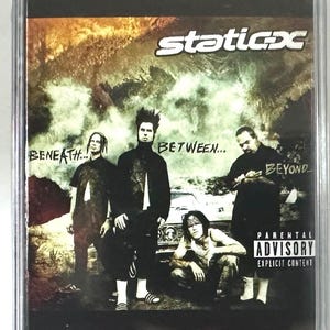 May include: A CD case featuring the band Static-X's album "Beneath... Between... Beyond." The cover art shows the band members in black and white, with the band's logo and album title in white. A parental advisory warning is visible.