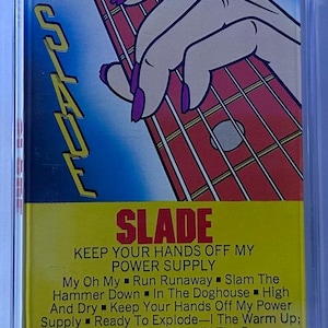 May include: A vintage cassette tape for the album "Keep Your Hands Off My Power Supply" by Slade. The cover features a hand with purple nails playing a red guitar, with the album title and tracklist in yellow.